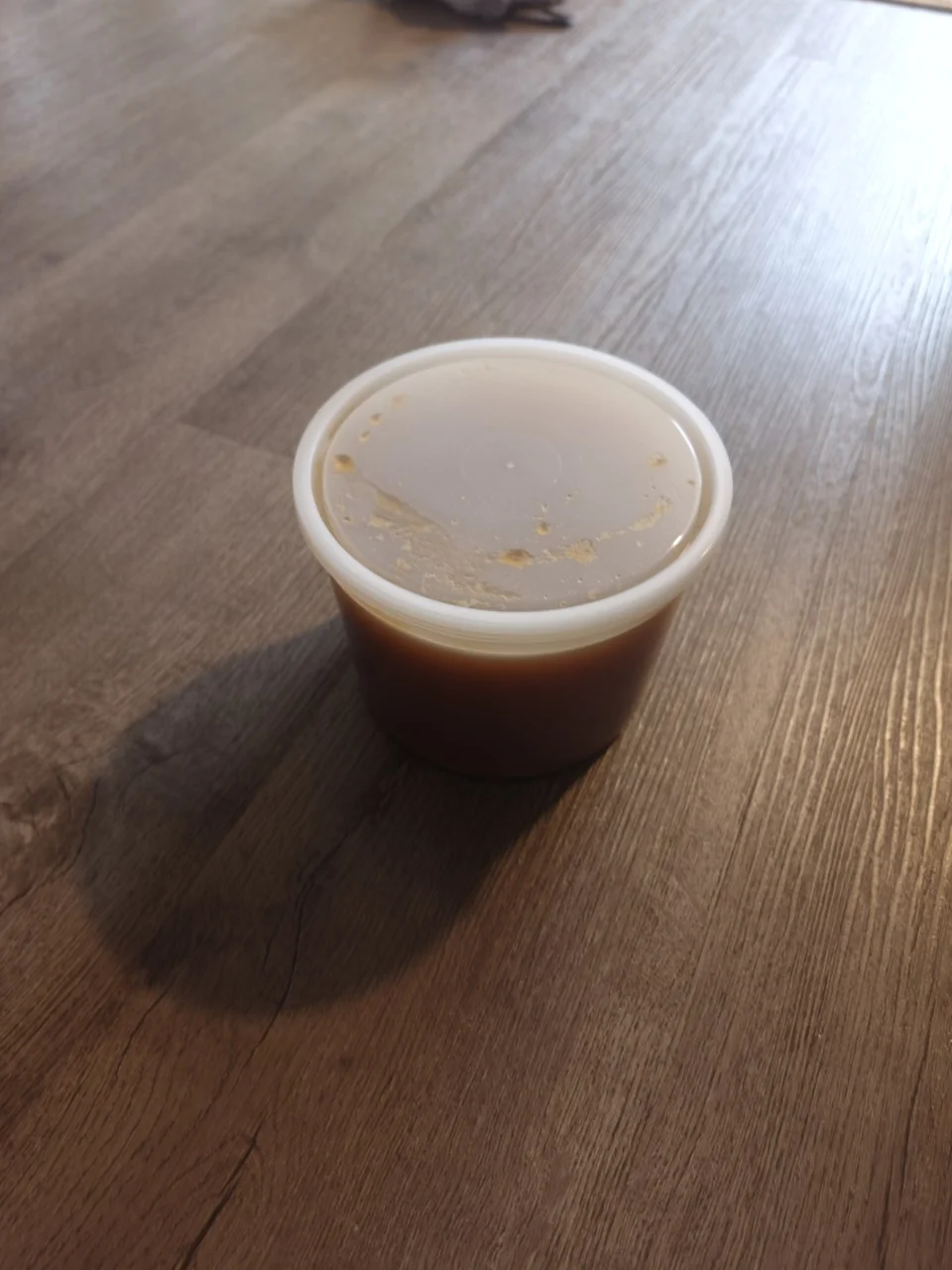 A lidded tub of Utah alfalfa honey on a wooden surface.